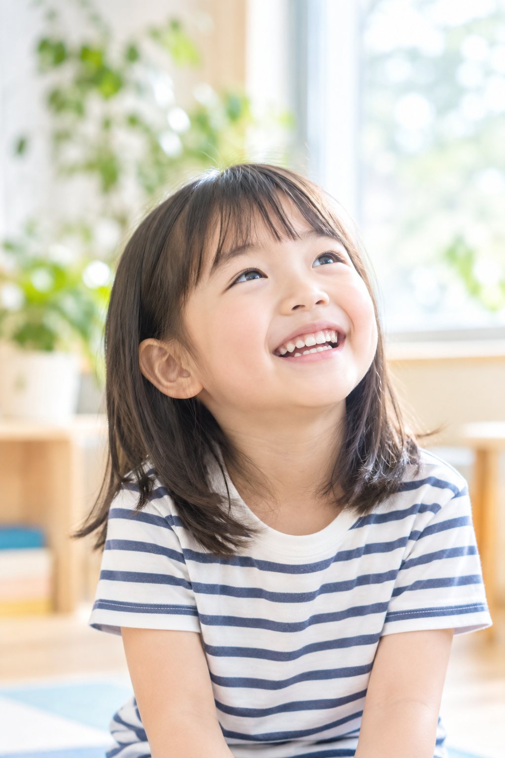 窓辺で上を見上げて笑う女の子