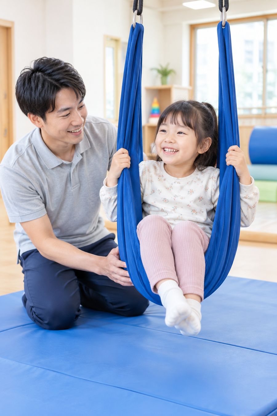 作業療法士がブランコに乗る女の子を支える様子